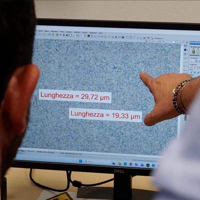 Misurazione della dimensione del grano su micrografia, con rilevazione delle dimensioni in micrometri.